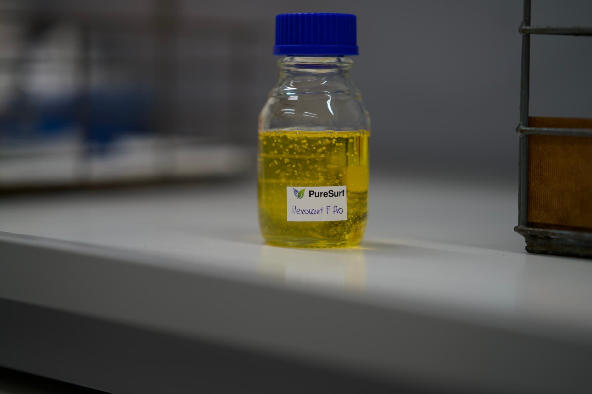 PureSurf Nexovant sample bottle holding yellow surfactant solution in the lab